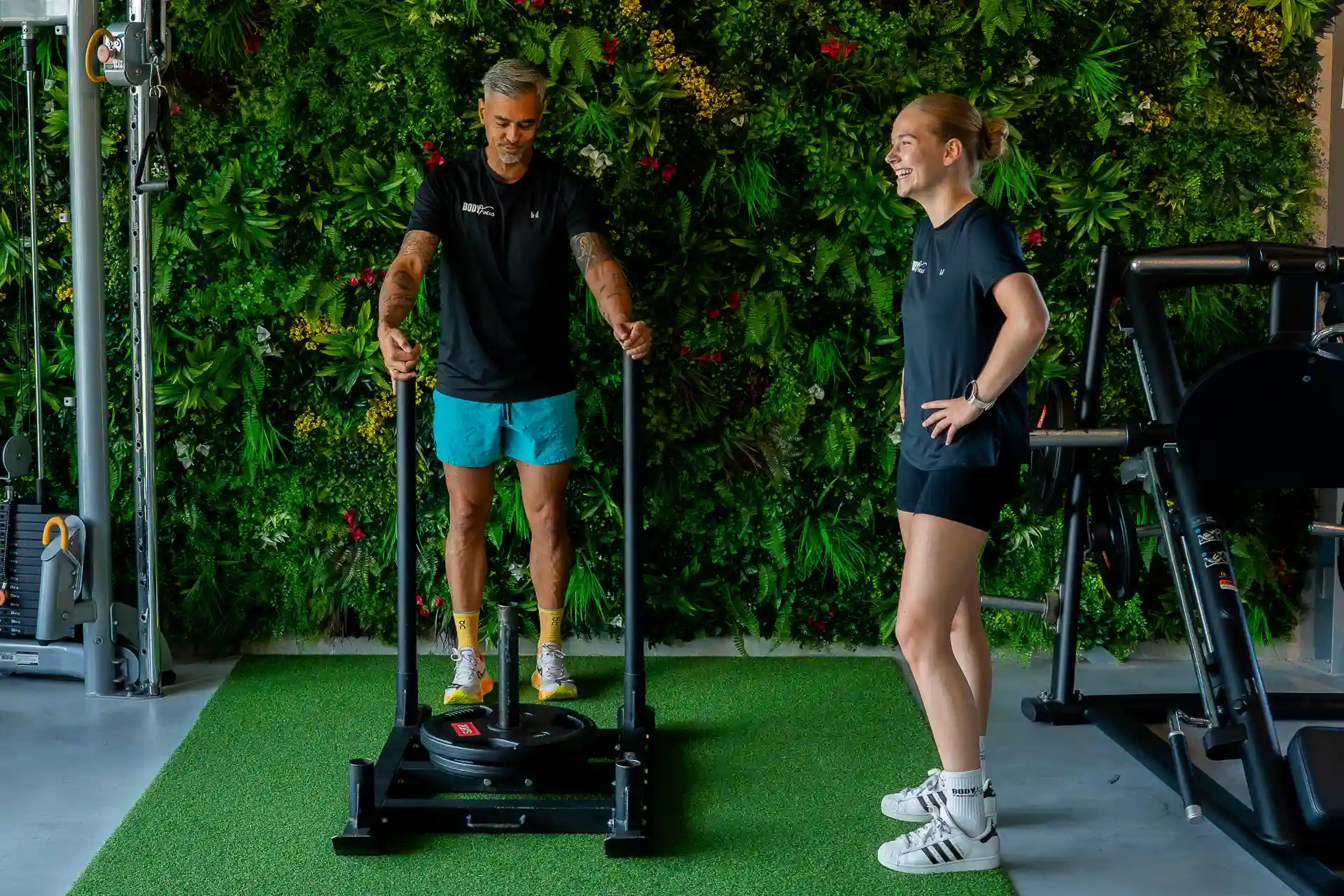 Twee sportmaatjes trainen samen met een sandbag lunge onder begeleiding van een Body Focus trainer