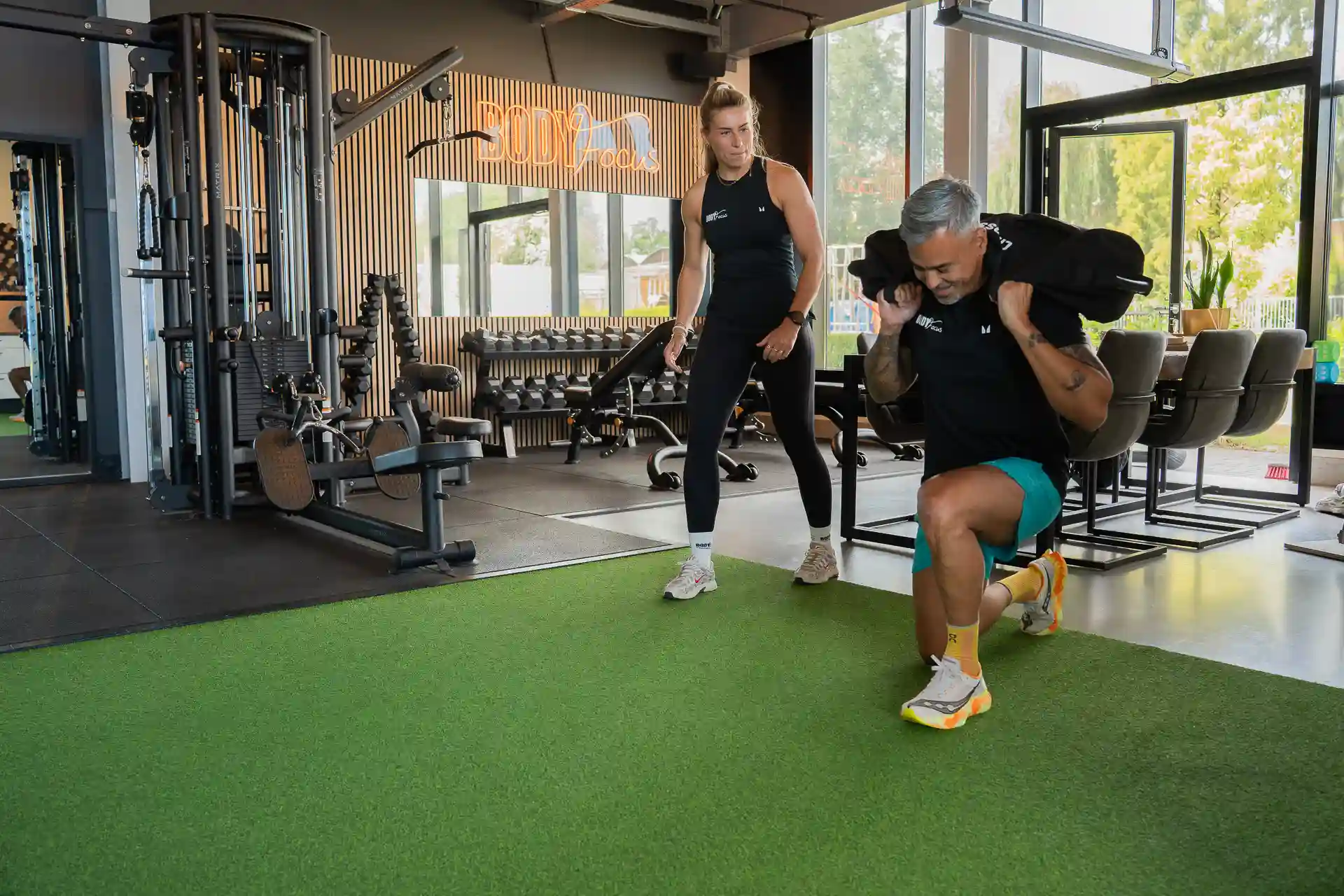 Lid duwt een sled met begeleiding van een Body Focus trainer tijdens hybride training